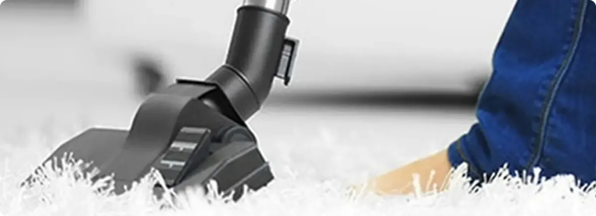 Close-up of a professional vacuuming a white carpet in Glenpool.